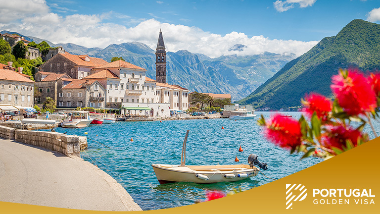 Scenic panorama view of the historic town of Perast at famous Bay of Kotor with blooming flowers on a beautiful sunny day with blue sky and clouds in summer, Montenegro